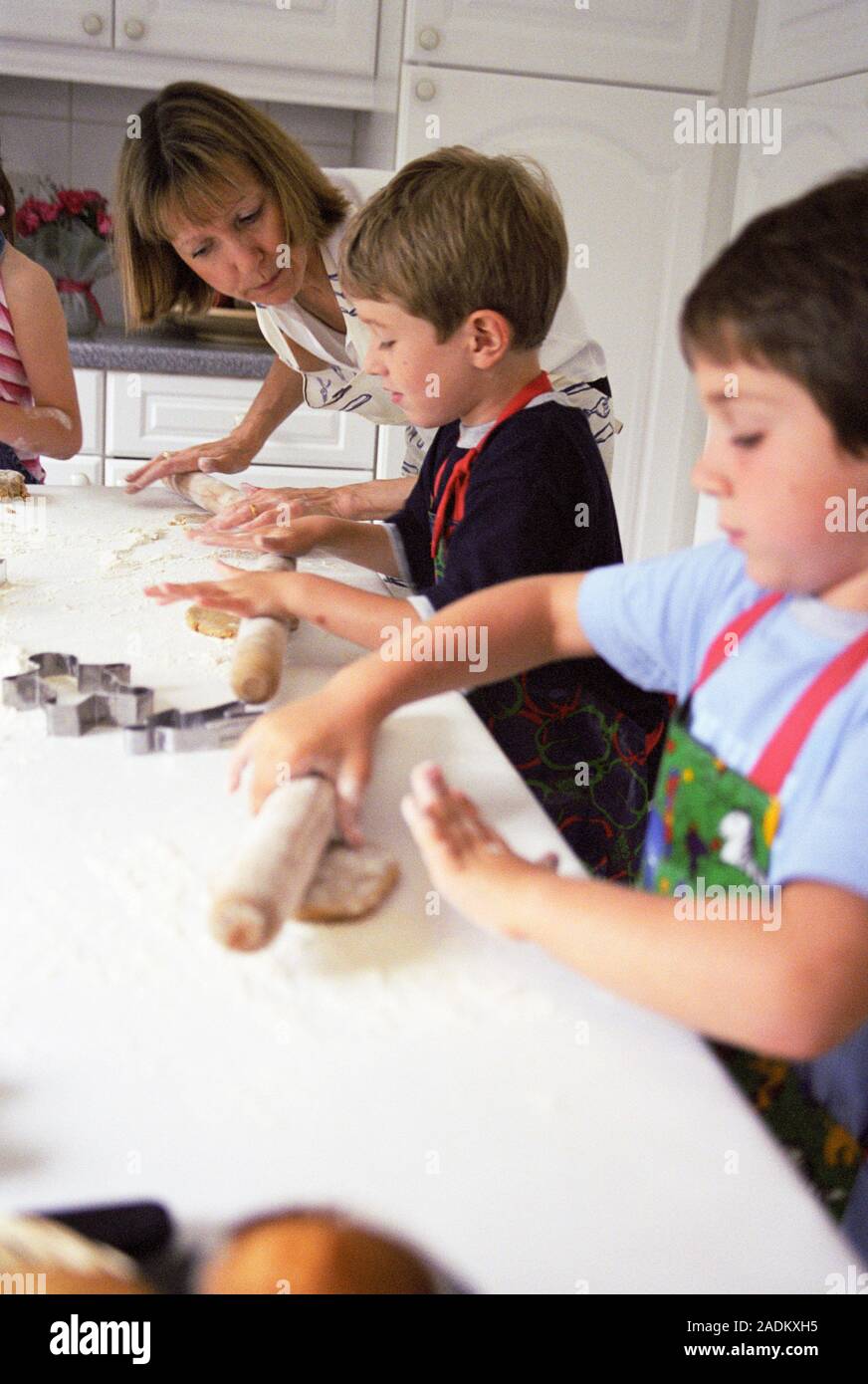 Making biscuits. 5-year-old boys being watched by an adult while they roll out biscuit dough. Biscuits will be cut out of the dough using shaped cutte Stock Photo