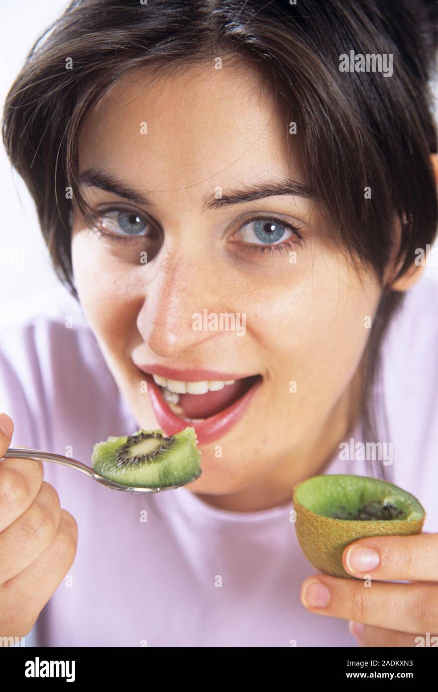 Healthy eating. Woman eating a kiwi fruit (Actinidia sp.). Kiwi fruits are rich in vitamin C