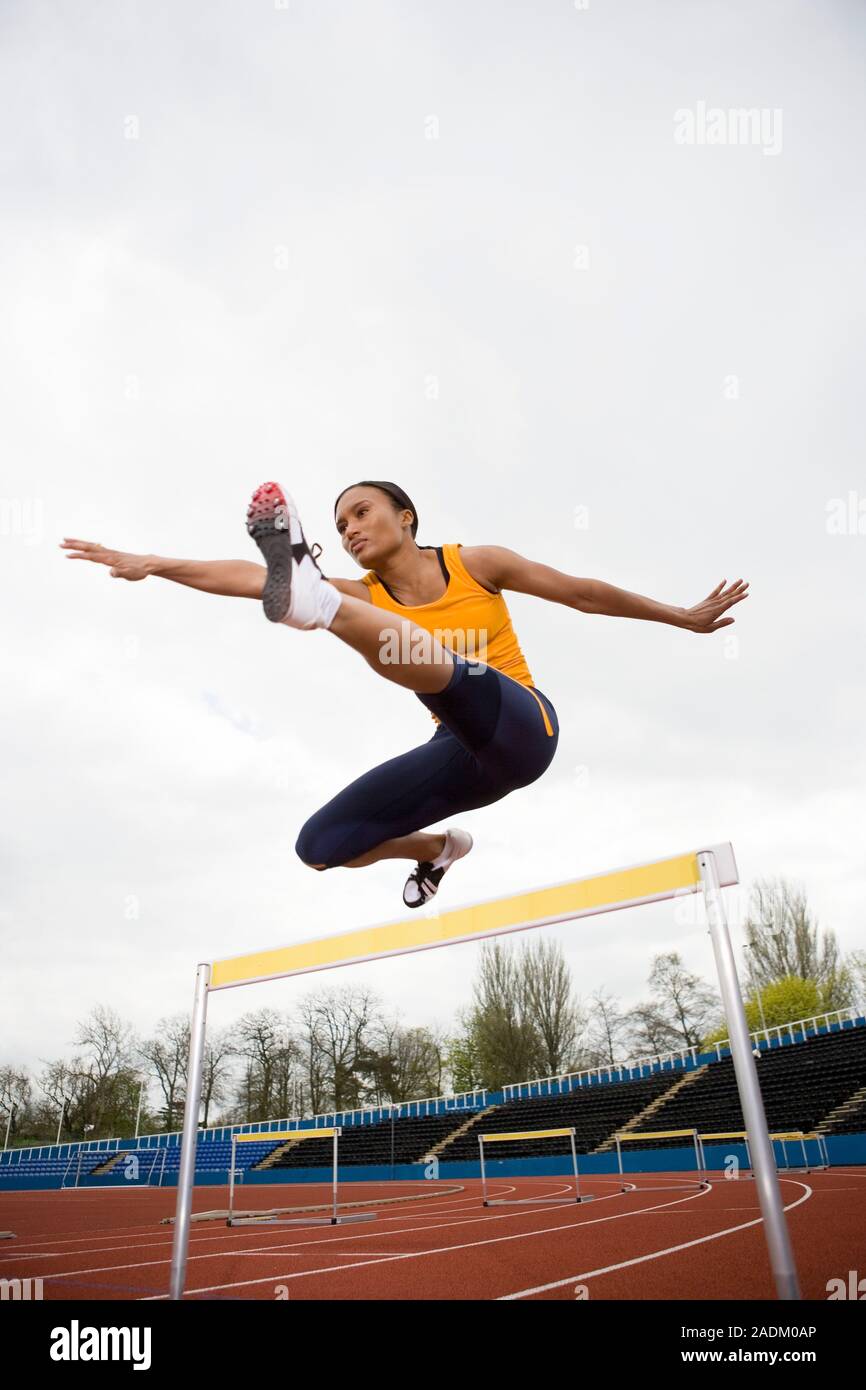 MODEL RELEASED. Athlete clearing a hurdle. Stock Photo