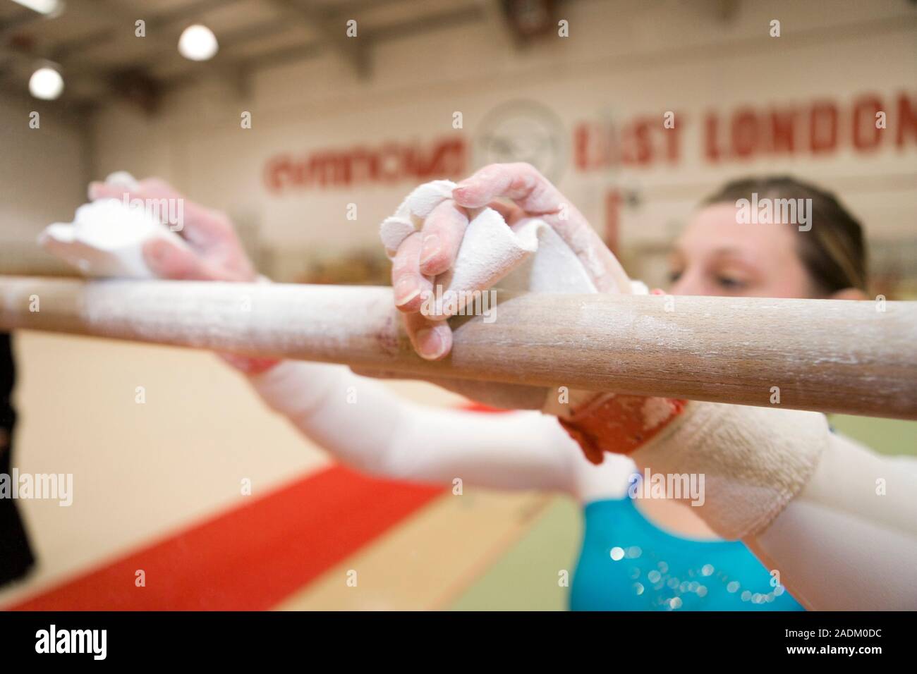 MODEL RELEASED. Gymnast rubbing chalk on a bar. Gymnasts rub chalk on