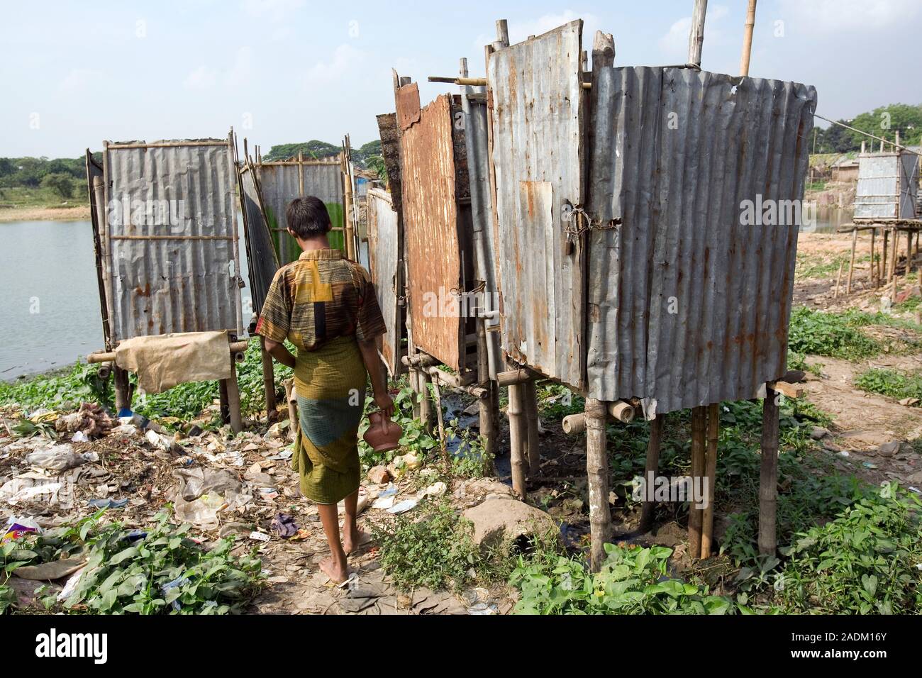 MODEL RELEASED. Slum toilets in Dhaka, Bangladesh. Man using a hanging