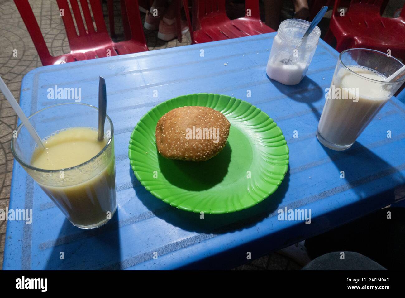 A sweet piece of bread and two cups of soy milk sold at a Vietnamese