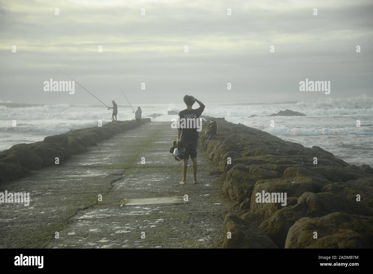 Barefoot young man looking out to sea, by pasakdek Stock Photo - Alamy