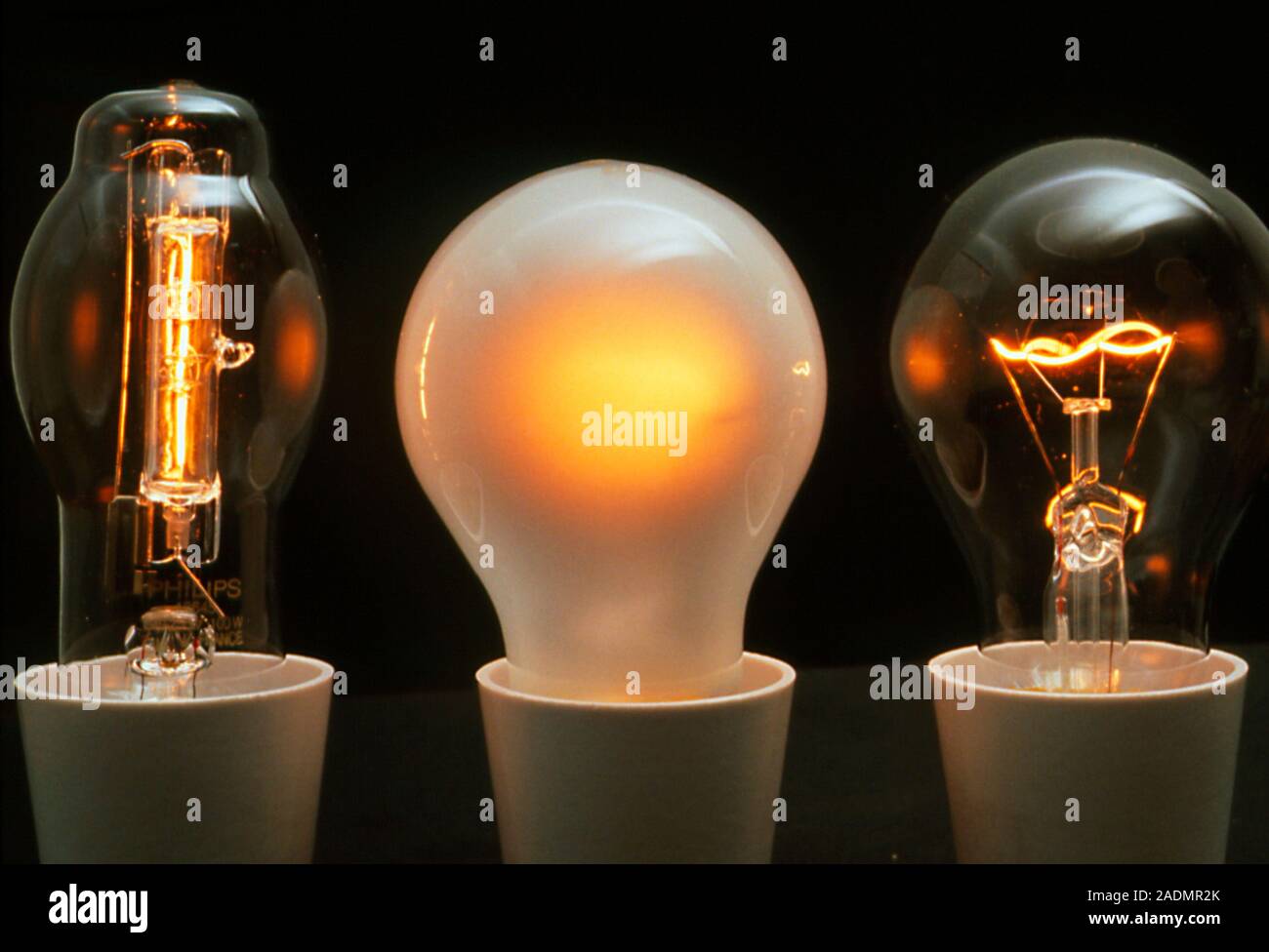 Three 100-Watt light bulbs. They are (left to right): halogen, pearl envelope and clear envelope. The halogen bulb has a tungsten filament surrounded Stock Photo