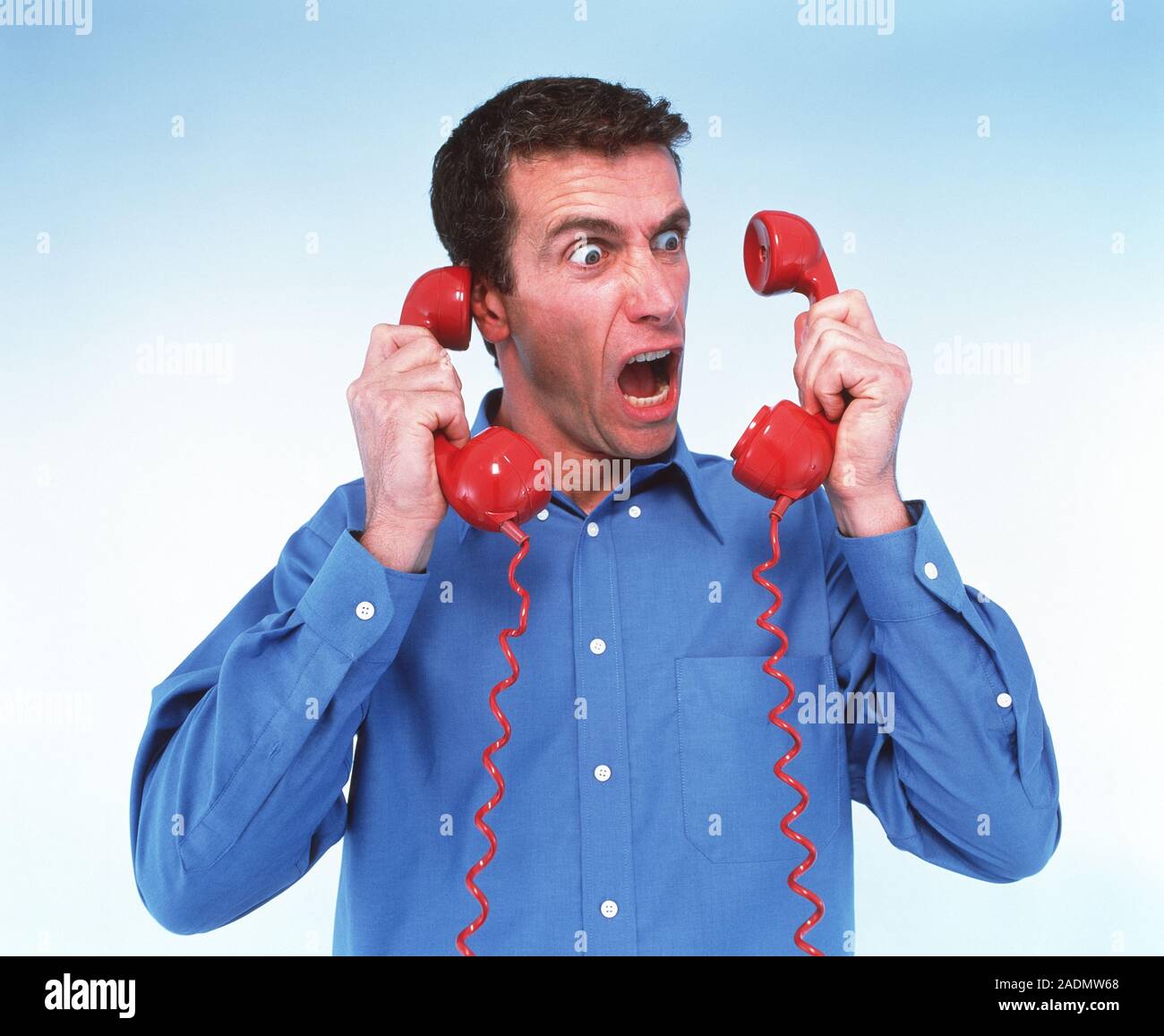 Telephone rage. Outraged man holding two telephone receivers Stock ...