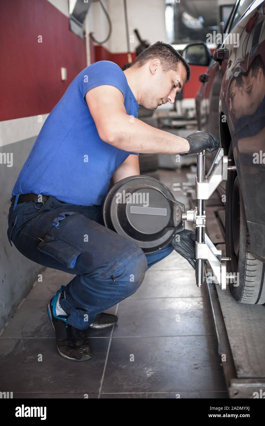 Car mechanic installing sensor during suspension adjustment. Wheel