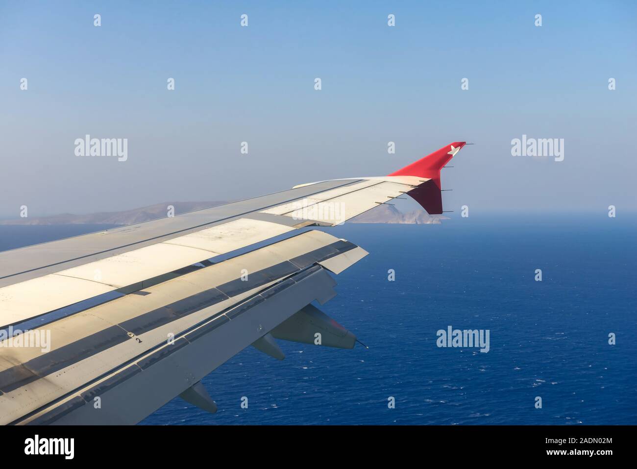 Wing of an airplane flying above the ocean. Stock Photo