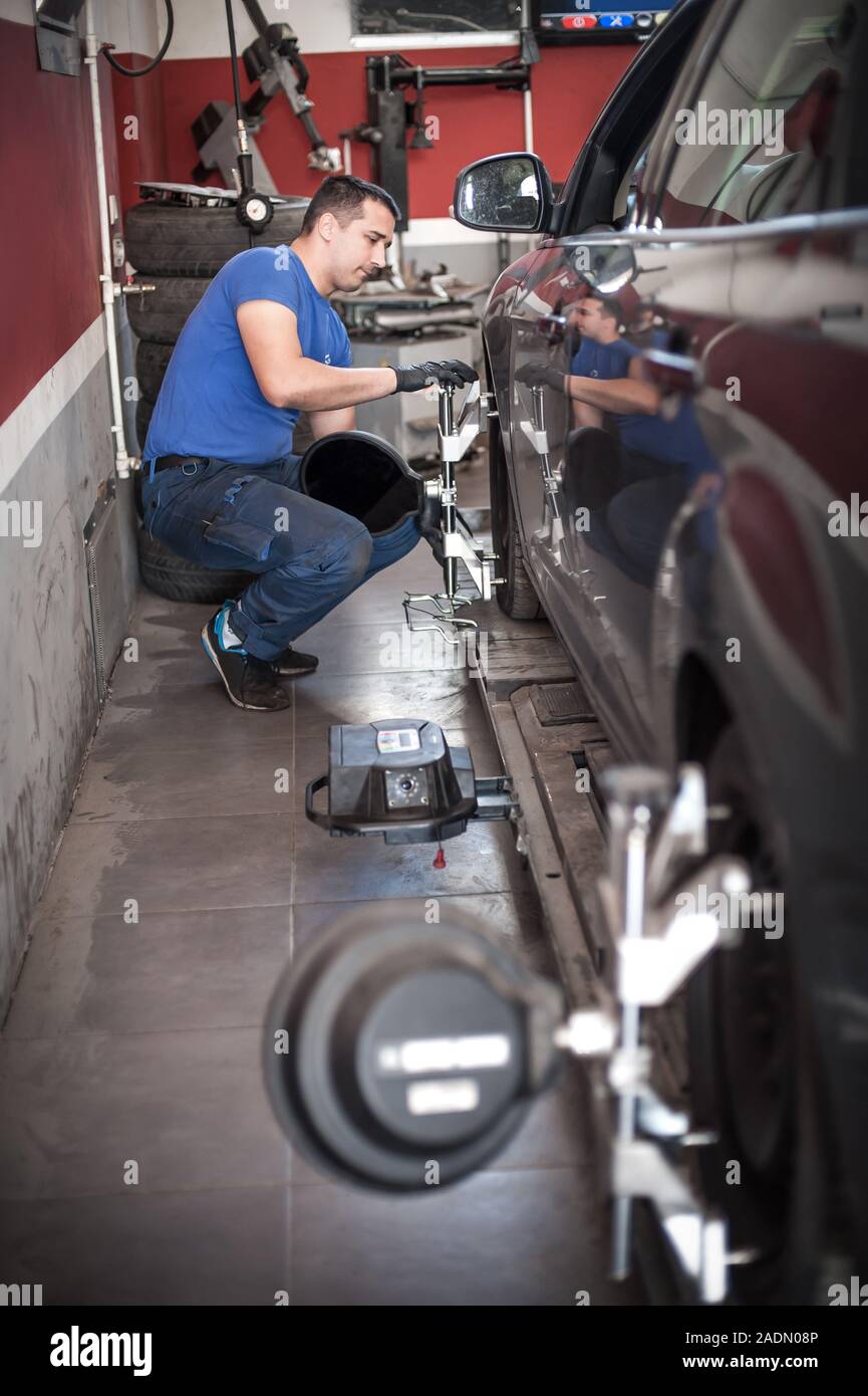 Car mechanic installing sensor during suspension adjustment. Wheel ...