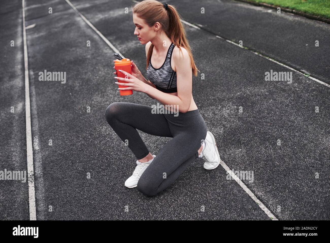 Training is over. Photo of fitness girl have a rest after morning run at the stadium Stock Photo