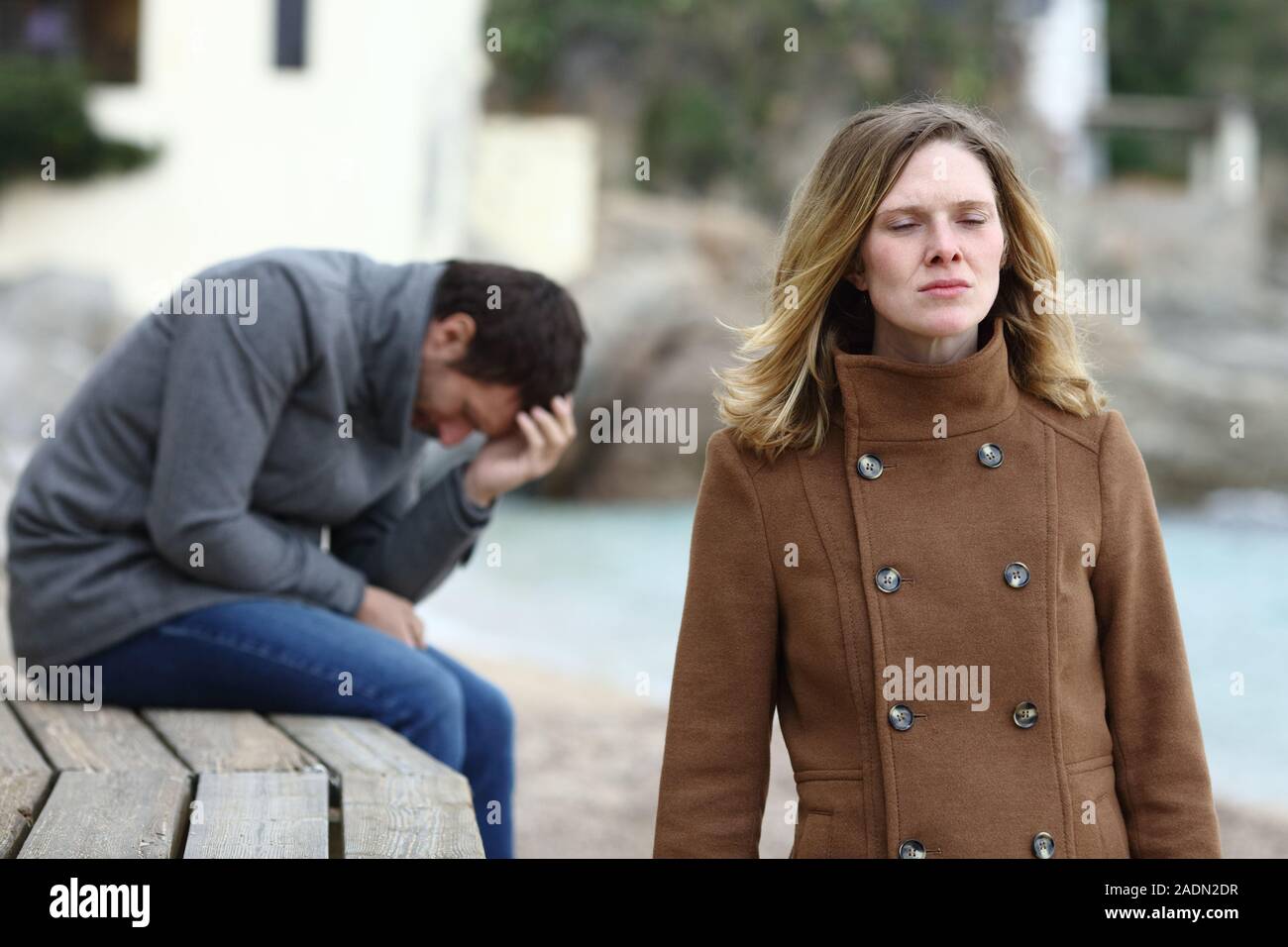 Sad boyfriend complaining after break up and angry girlfriend leaving him in winter Stock Photo
