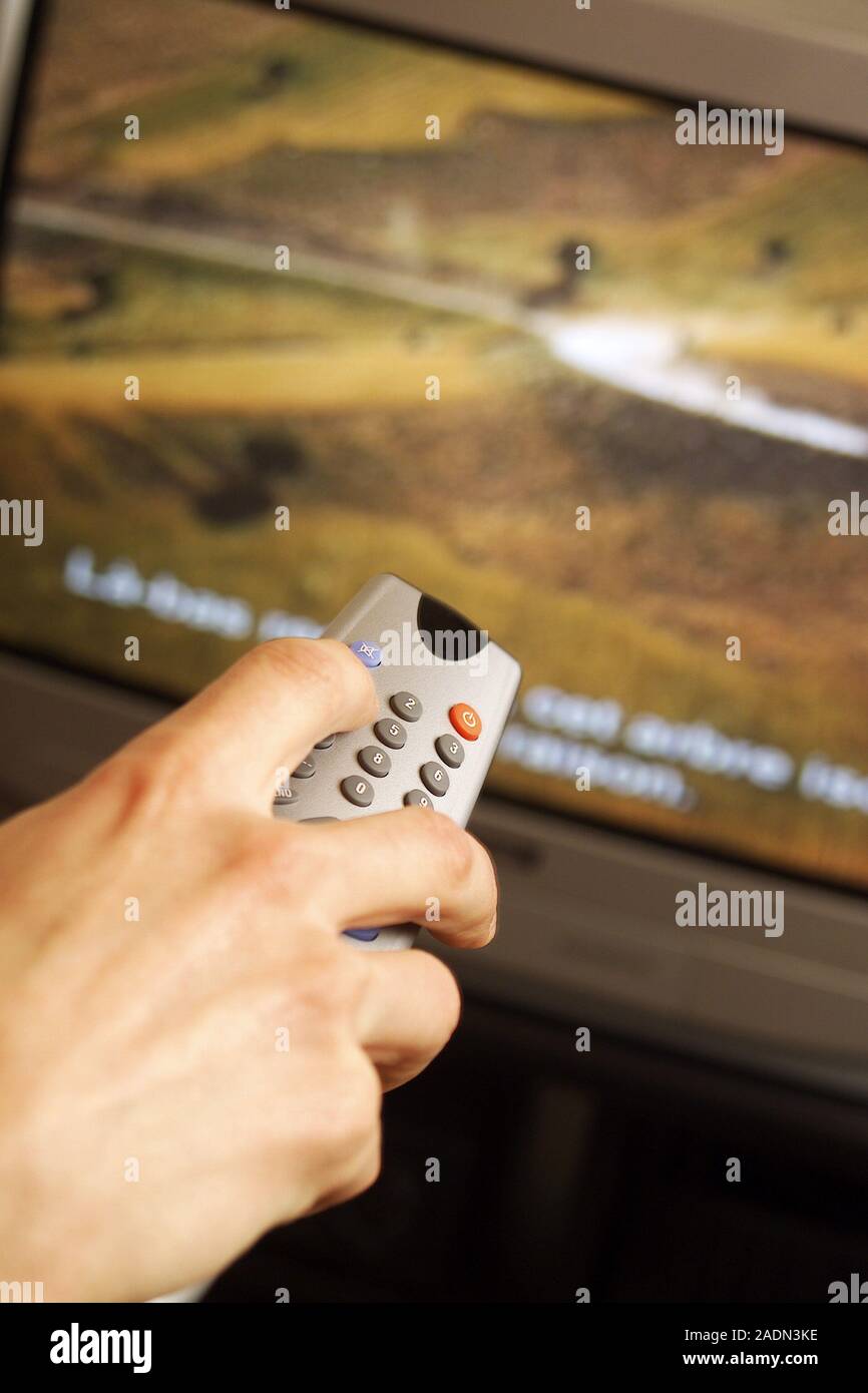 Remote control being used to change channels on a television stock