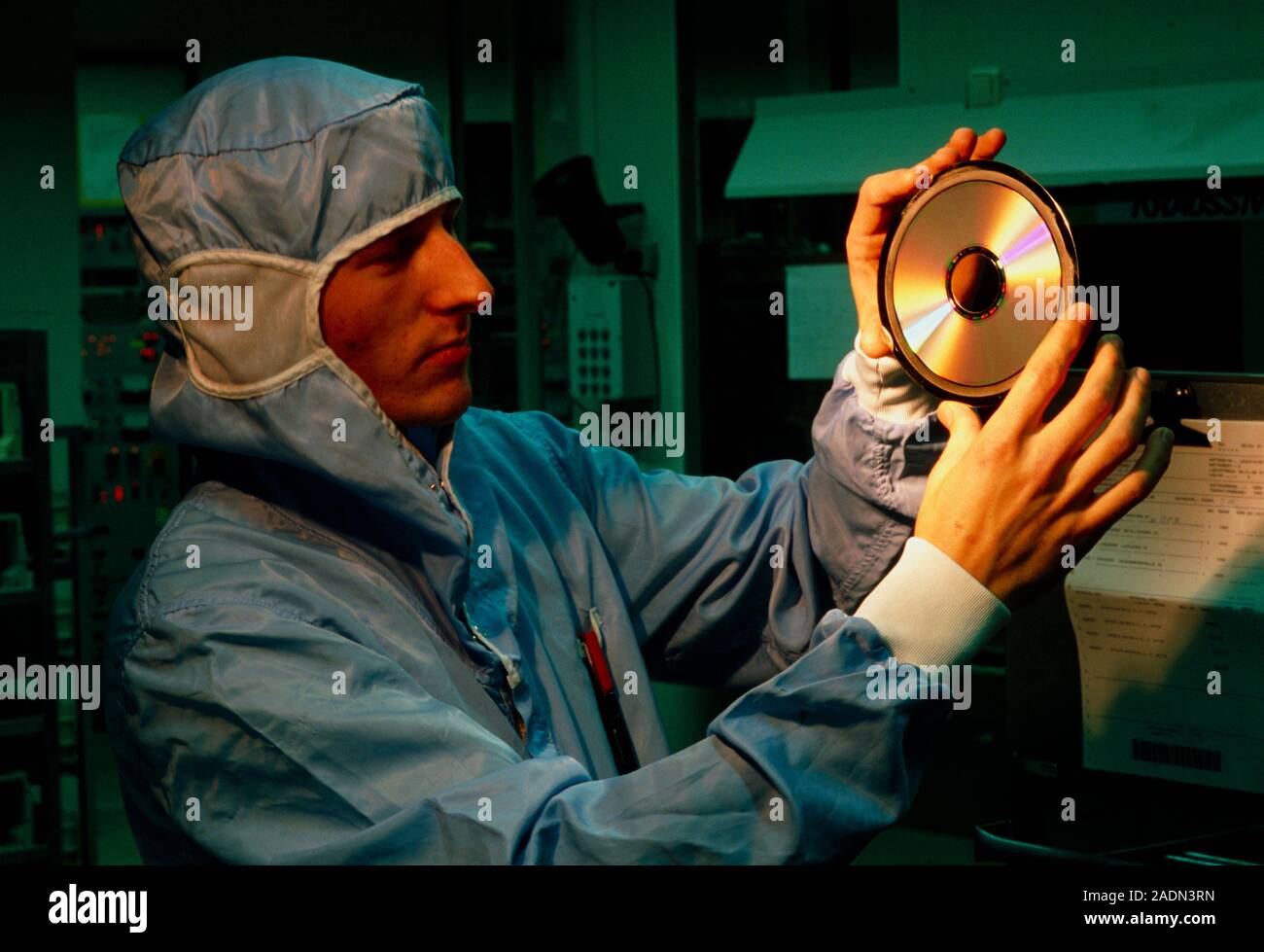 Compact disc production. Technic- ian in clean room clothing visually ...