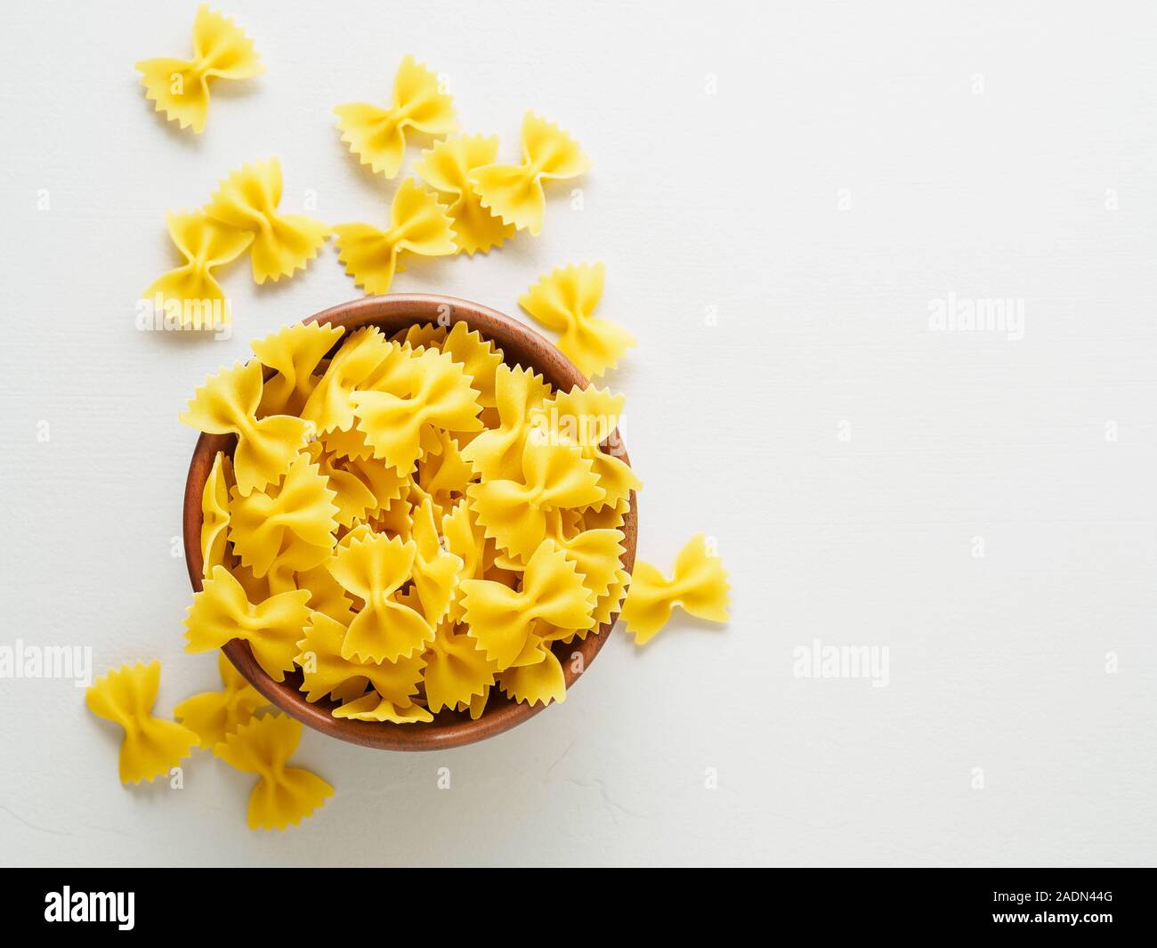Pasta farfalle in wooden bowl on gray stone table. Top view, empty place for text. Stock Photo