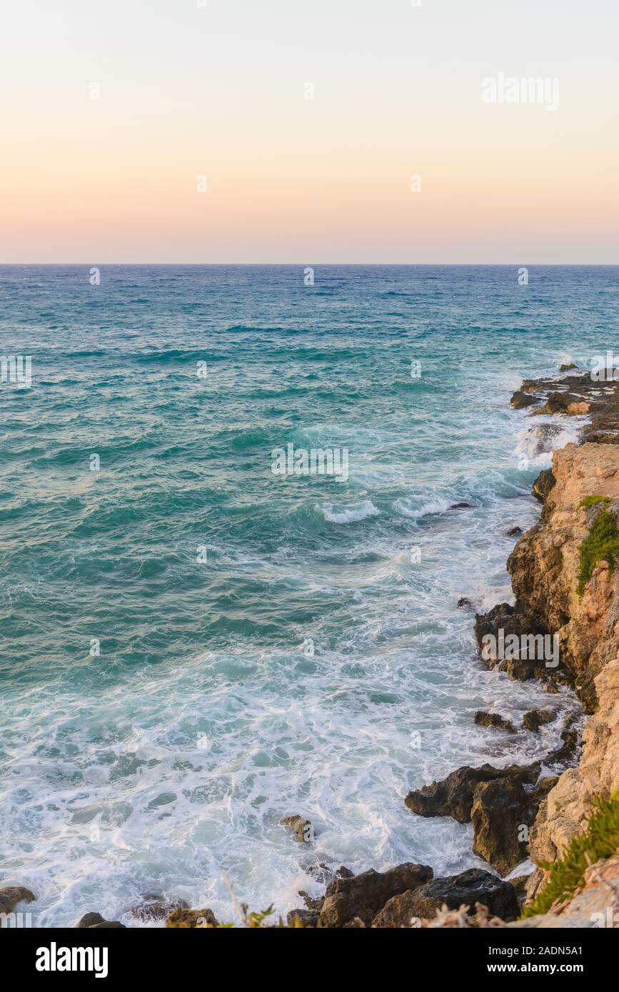 Rocks, waves and Surf on the coast and beach. Beautiful blue open wavy ocean in summer time. Sea at sunset. Rocks. Stock Photo