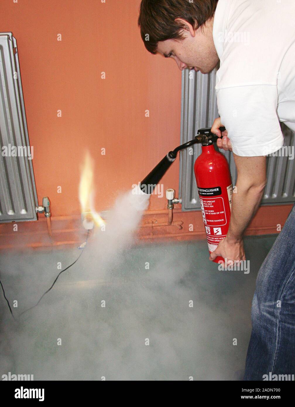 MODEL RELEASED. Electrical fire. Man fighting an electrical fire with a