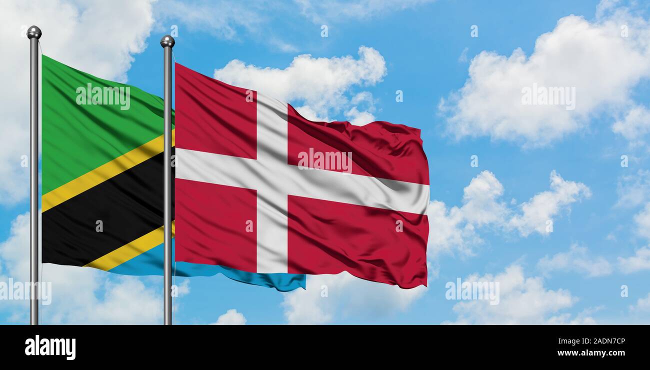 Tanzania and Denmark flag waving in the wind against white cloudy blue sky together. Diplomacy concept, international relations. Stock Photo
