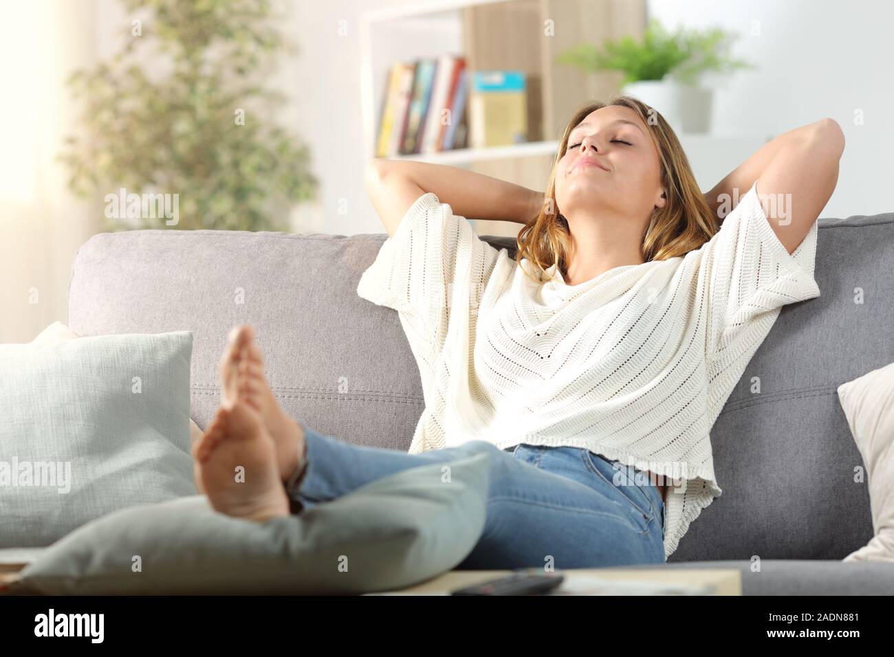 Carefree Woman Relaxing Sitting On A Sofa In The Living Room At Home