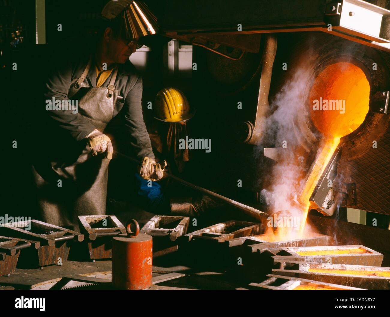 Precious metal recycling. Worker pouring molten recycled precious metal