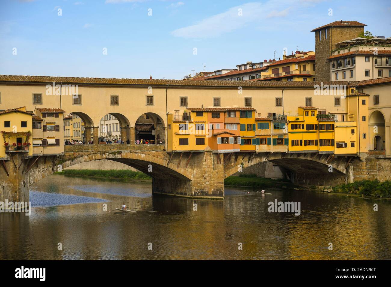 View of the famous Ponte Vecchio bridge in the historic centre of Florence, Unesco W.H. Site, with two men rowing on the Arno River, Tuscany, Italy Stock Photo