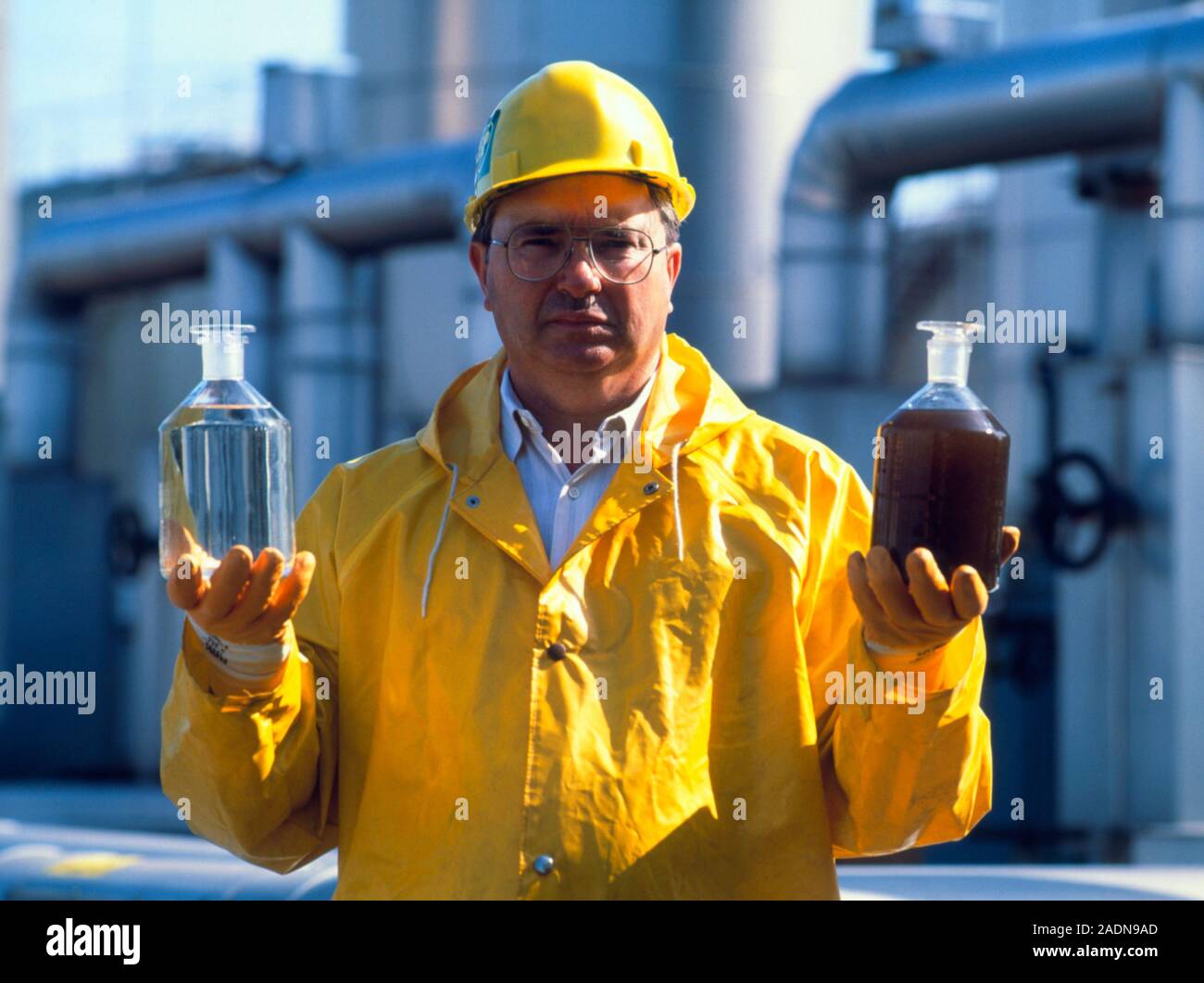 Sewage treatment. Worker holds samples of treated and untreated sewage