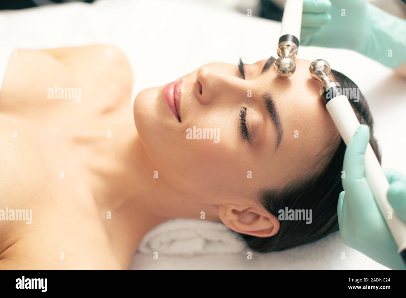 Peaceful woman closing her eyes during the microcurrent therapy Stock Photo
