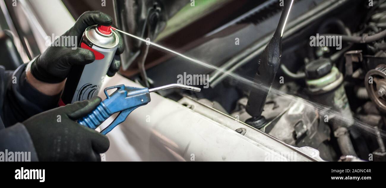 Car master mechanic repairer lubricates the screws with a machine parts cleaner oil dirt grease