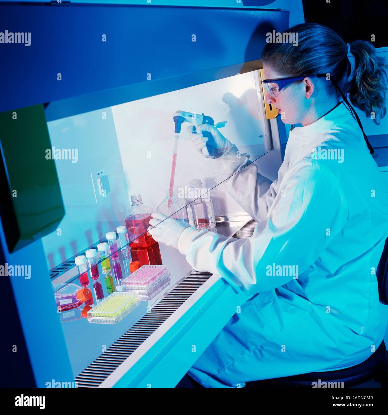 Chemist pipetting liquids in a fume cupboard. Fume cupboards extract