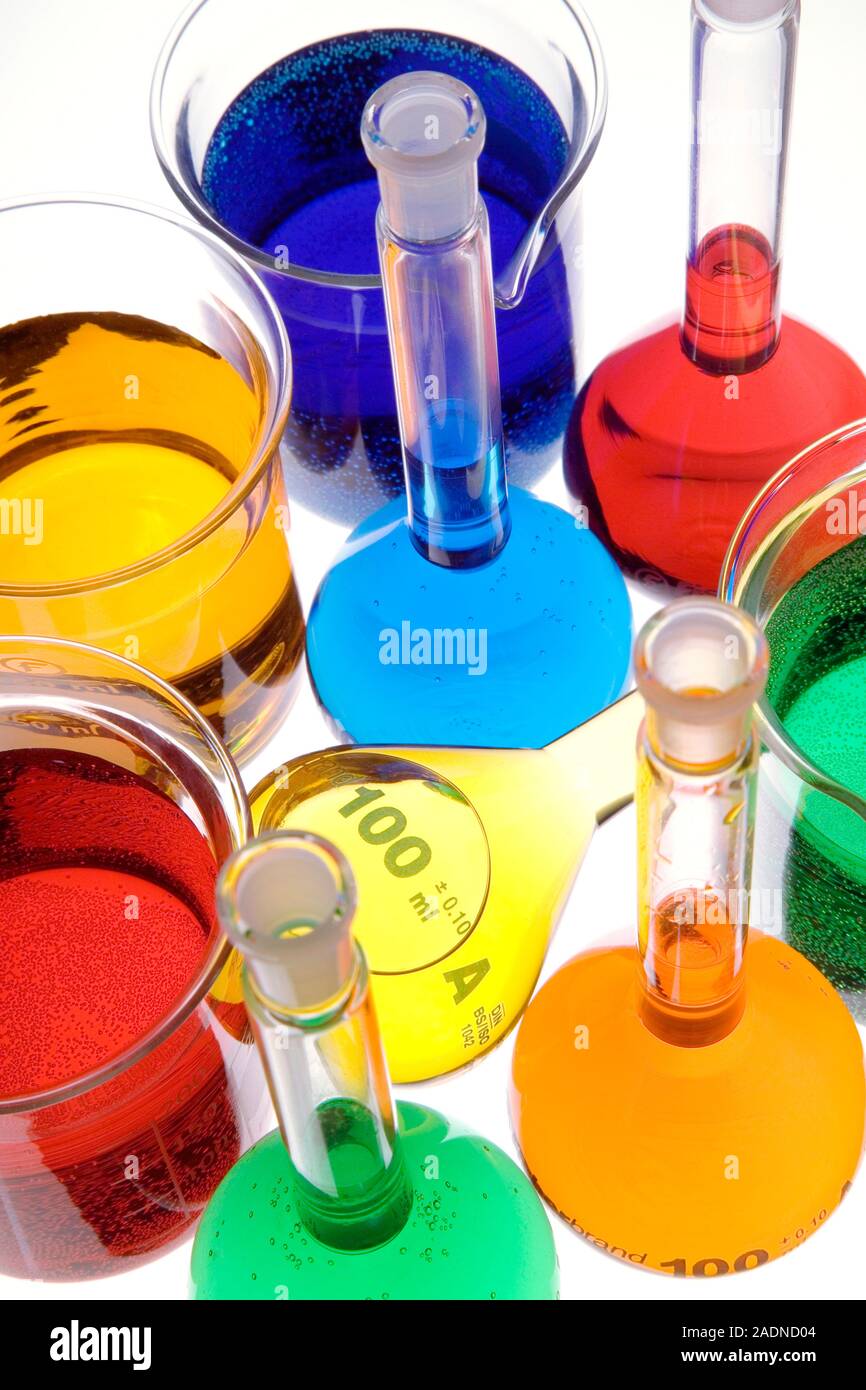 Laboratory glassware. Beakers and volumetric flasks containing coloured