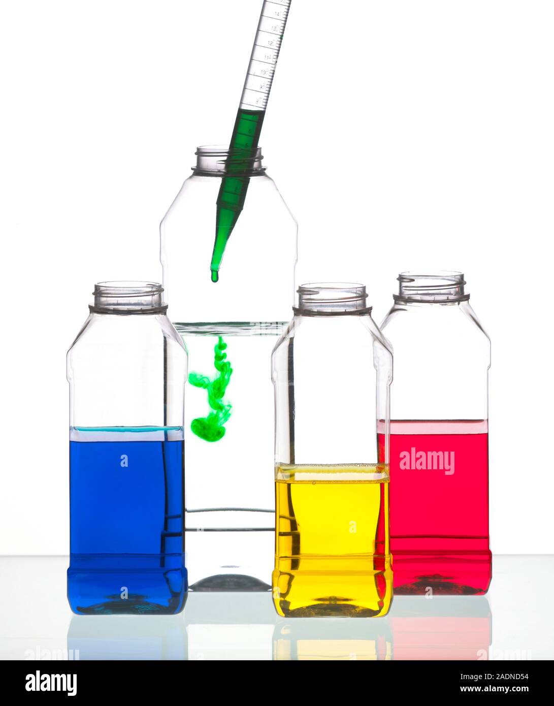 Pipetting. Pipette being used to add a green liquid to a plastic laboratory container Stock