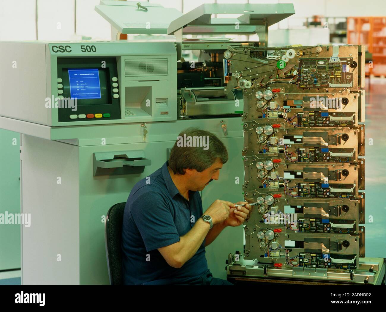 POSED BY MODEL. Cash dispenser manufacture. Technician adjusting a bank