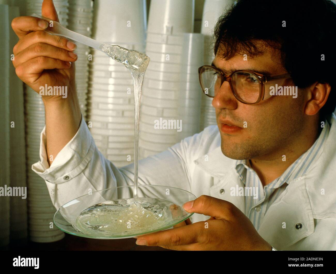 Plastics research. Scientist examines a solidifying resin as part of plastics research. Resins