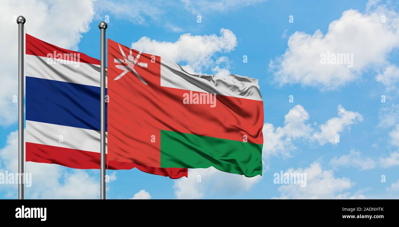 Thailand and Oman flag waving in the wind against white cloudy blue sky together. Diplomacy concept, international relations. Stock Photo