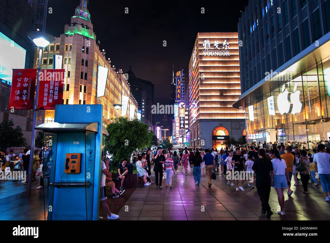 Shanghai, China - August 7, 2019: Nanjing road in downtown Shanghai with neon signs and shops and tourists walking around at night Stock Photo