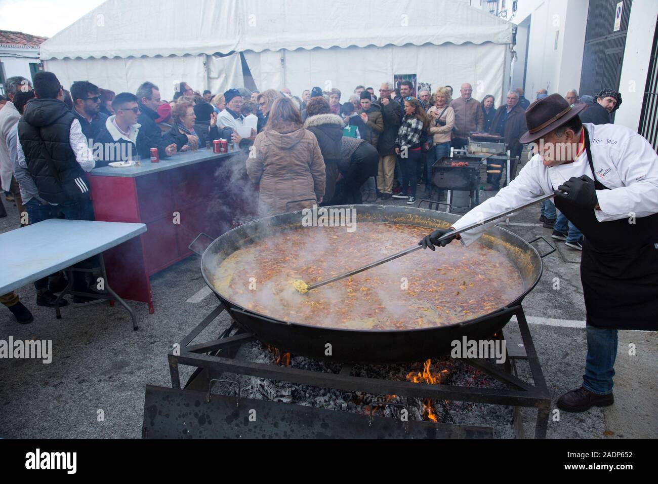 A man stirs an enormous dish of paella cooking over a firepit in Canillas de Albaida, Andalusia, Spain. Stock Photo