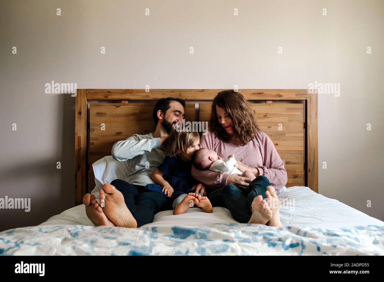Family With Newborn And 4 Yr Old Girls Cuddle Together On