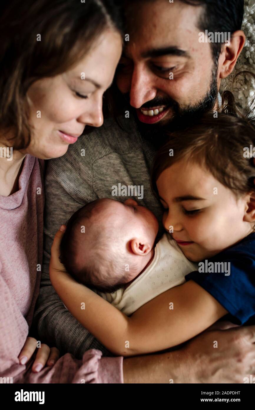 Family with closed eyes cuddled together embracing newborn Stock Photo