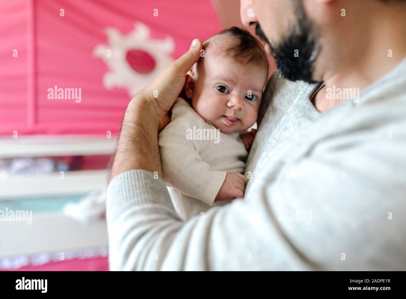 Tender father with beard cuddling infant with big brown eyes Stock Photo