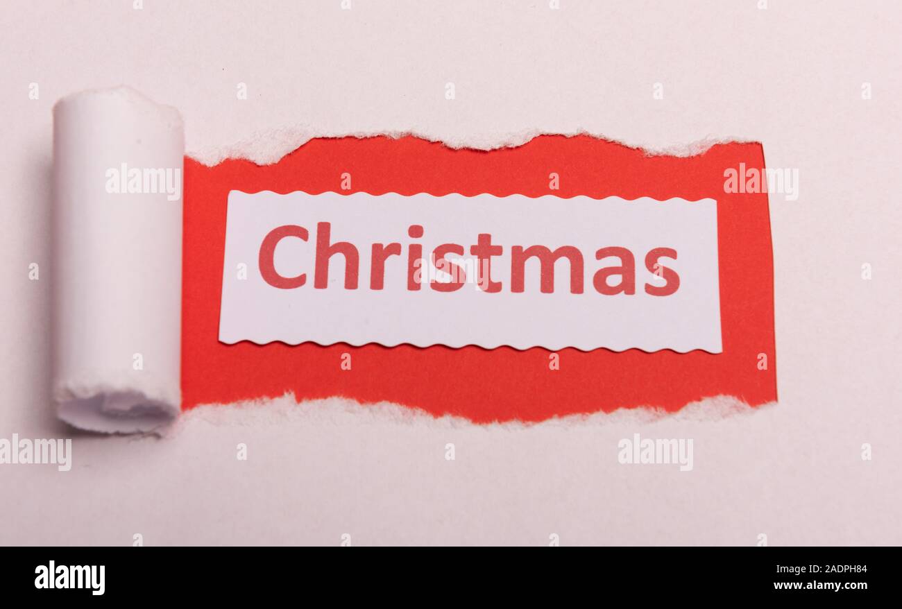 White torn paper with CHristmas text with red background color. Hidden message. Secret. Copy space Stock Photo