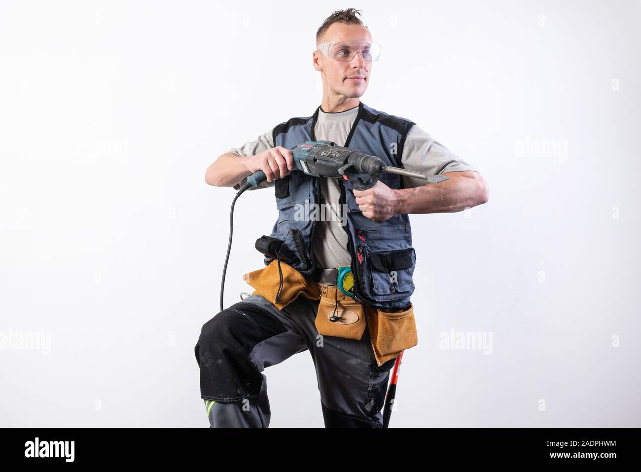 Builder with a drill in his hands, in unloading, aims to the right. Stock Photo