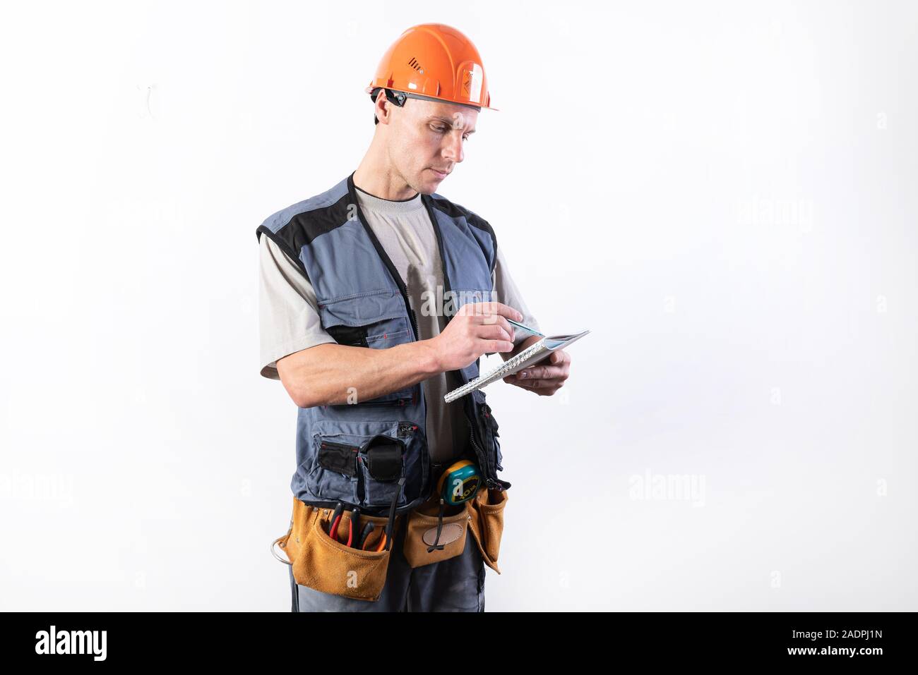 Builder with a notepad. In a helmet and a robe. Writes data. Stock Photo
