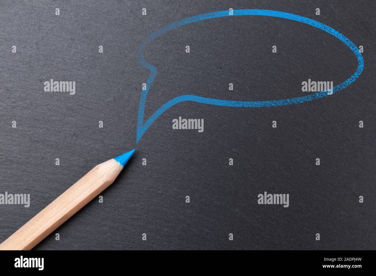 Blue color pencil with blue speech bubble above it, on chalkboard background, copy space Stock Photo