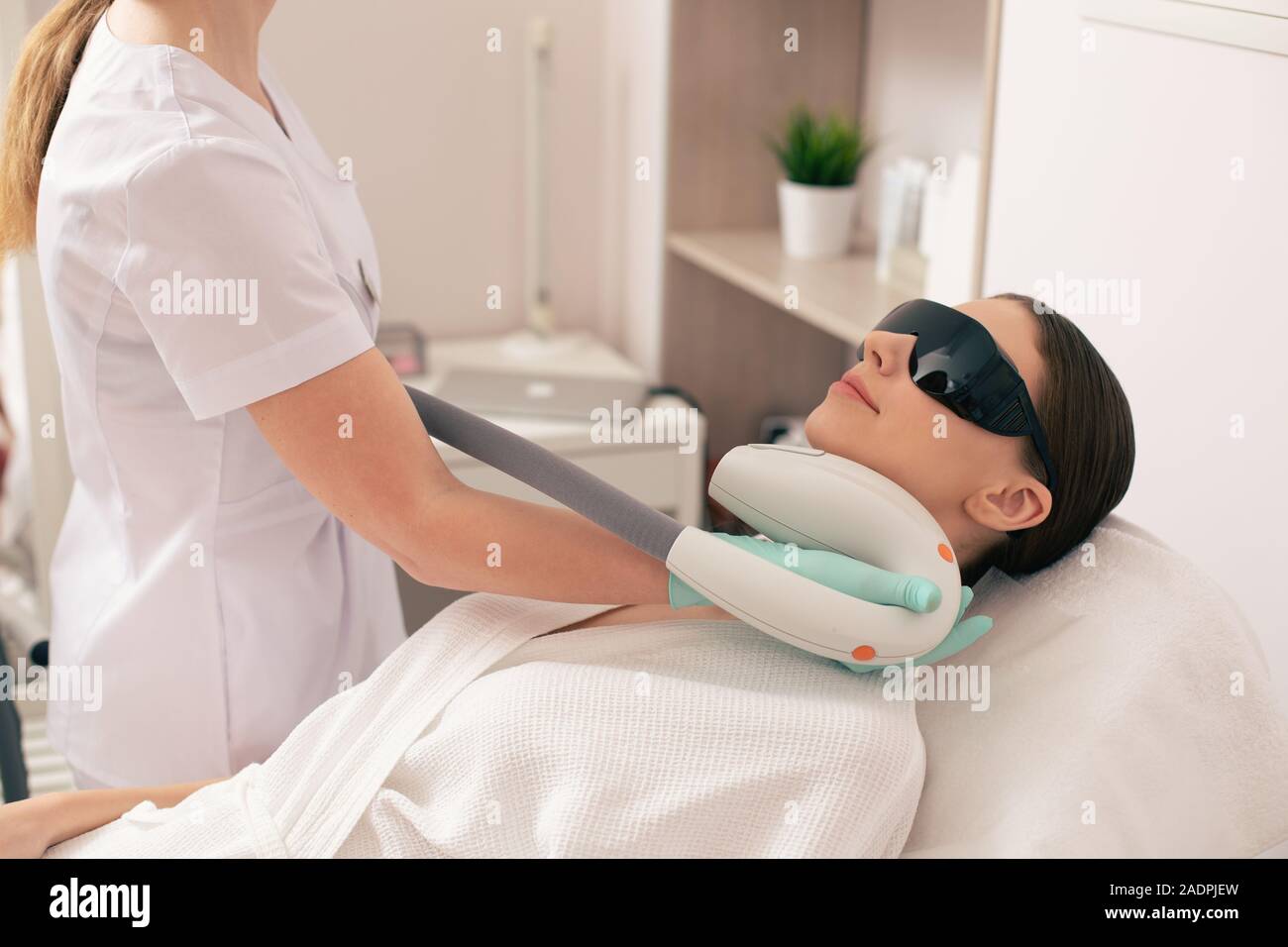 Cosmetologist using special device for laser hair removal on the neck