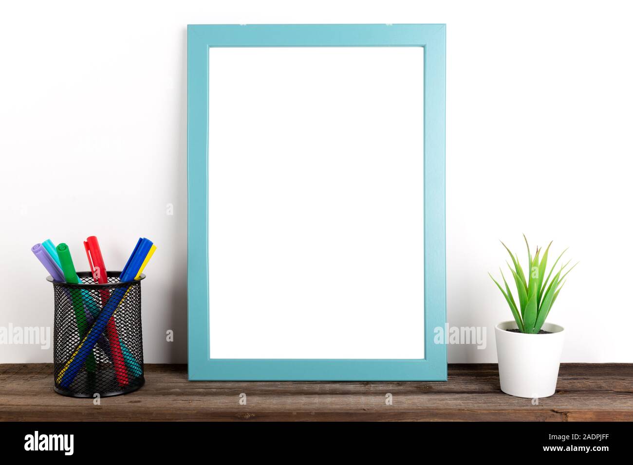 Interior poster mock up with vertical wooden frame, colored pencils and house plants on white wall background Stock Photo