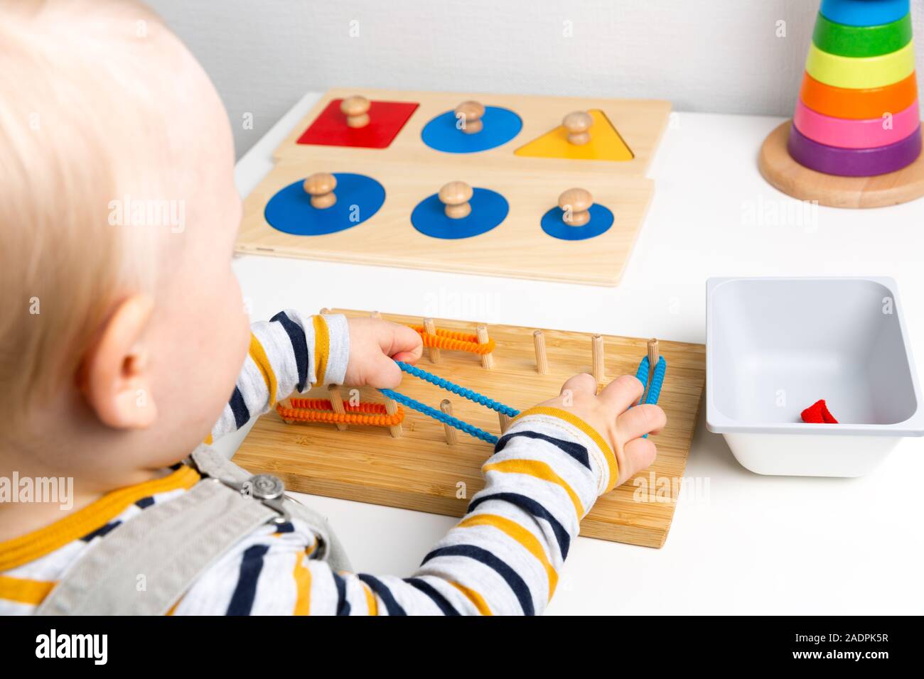 Child works with Montessori material for fine motor skills, sensory