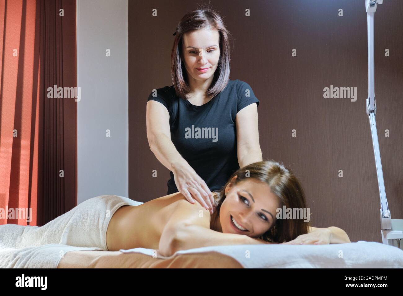 Mature woman lying on massage table and receiving medical back massage Stock Photo