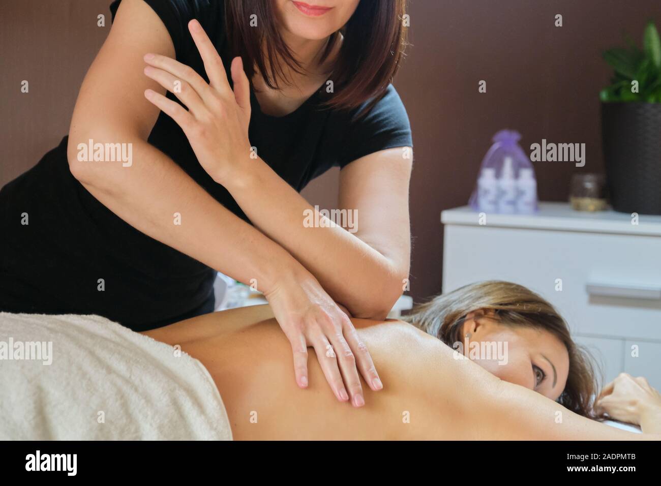 Mature woman lying on massage table and receiving medical back massage Stock Photo