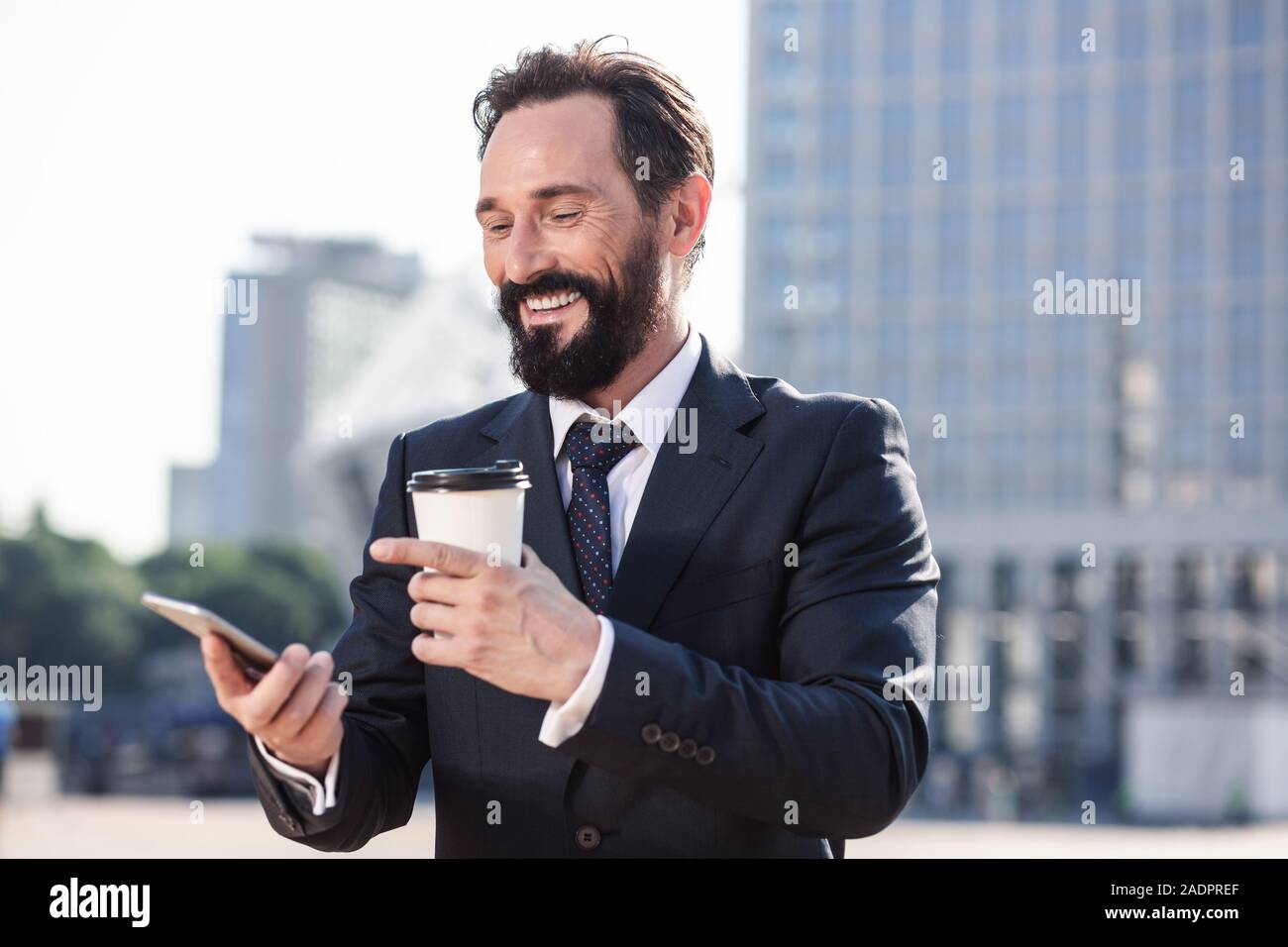 Waist up of a joyful businessman using his phone Stock Photo