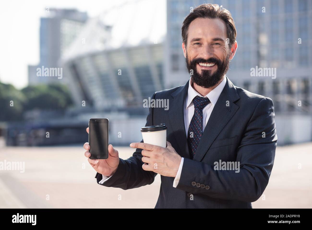 Cheerful bearded businessman holding a modern smartphone Stock Photo