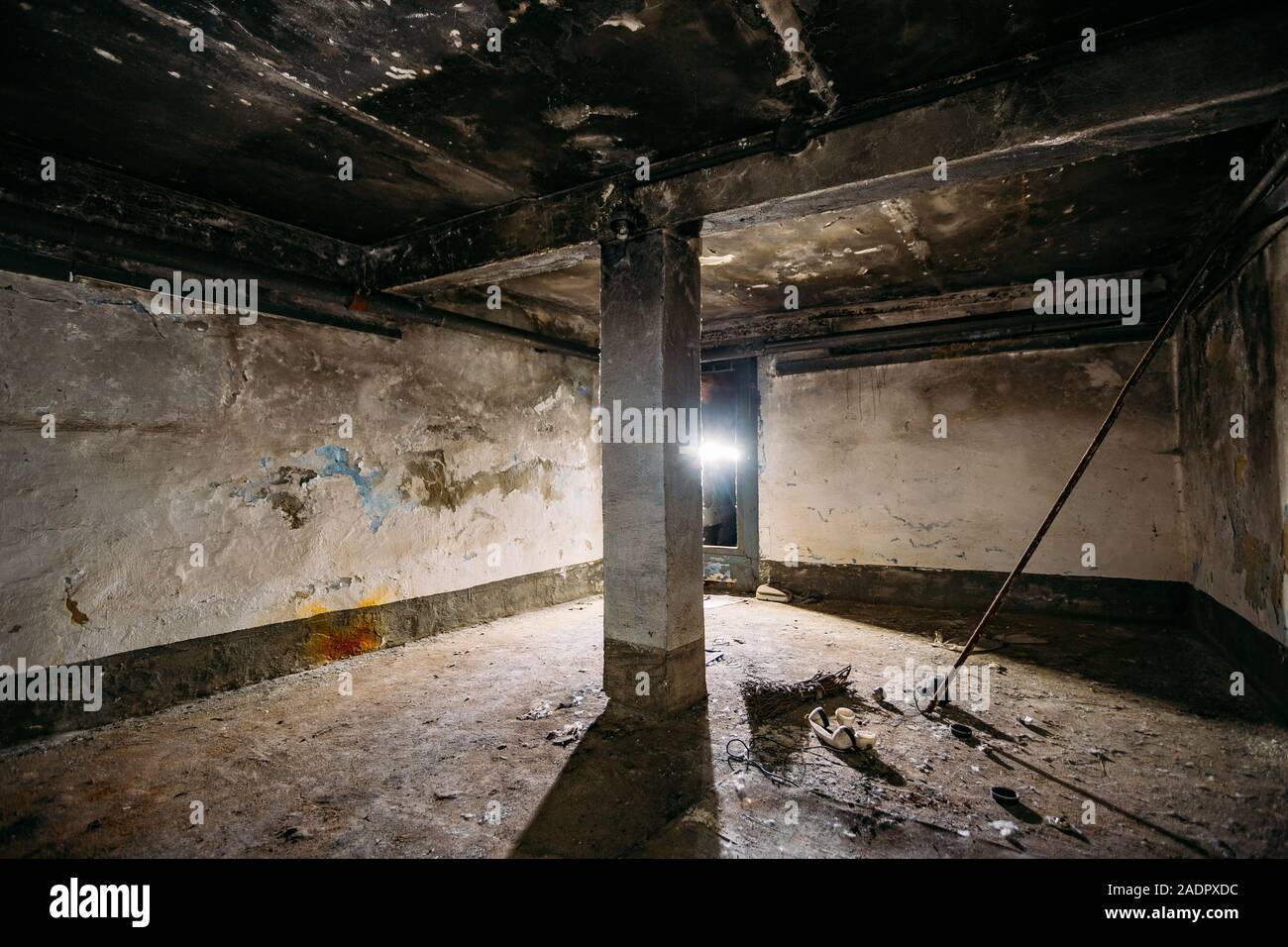 Dark and creepy dirty abandoned underground basement afrer fire. Walls in black soot Stock Photo