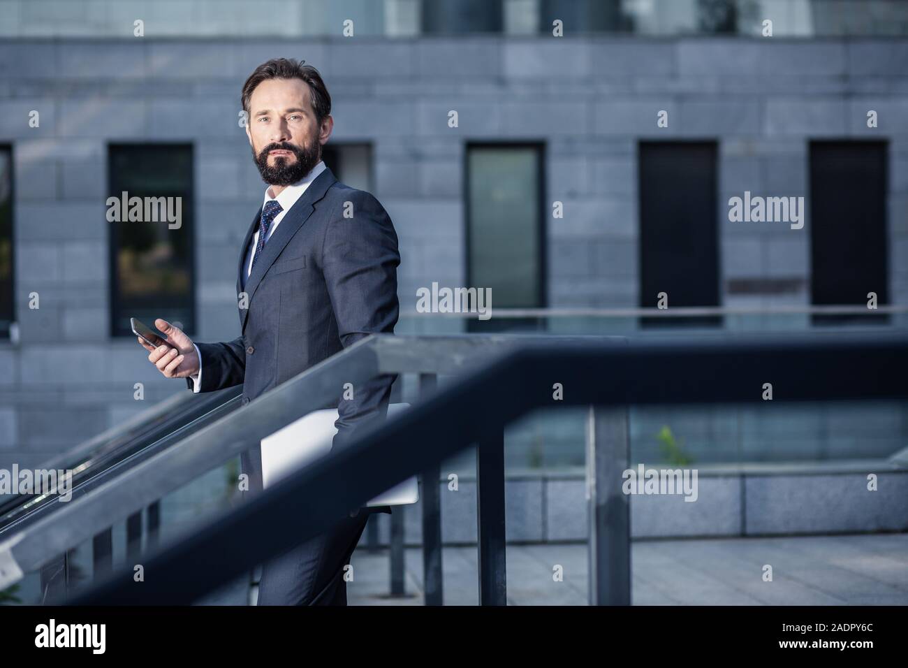 Serious businessman using his phone while looking at you Stock Photo